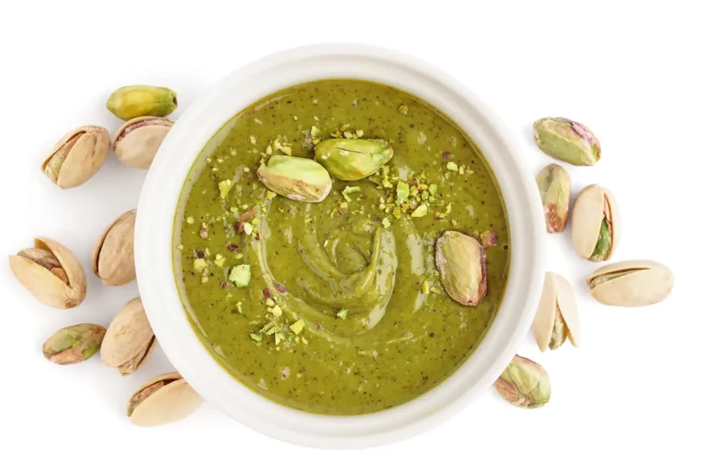 Bowl of pistachio cream surrounded by shelled pistachios