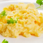 Plate of fluffy scrambled eggs garnished with fresh parsley