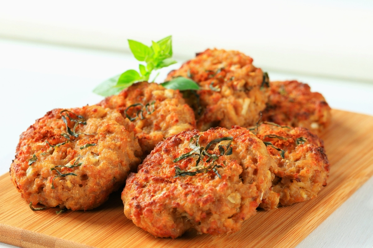 Golden-brown turkey sausage patties garnished with fresh herbs, served on a wooden board.