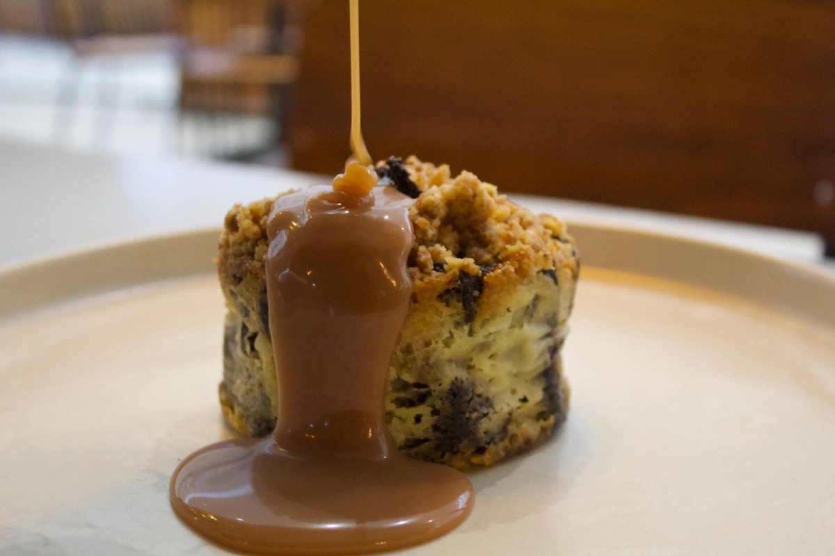 White chocolate bread pudding drizzled with caramel sauce on a plate.