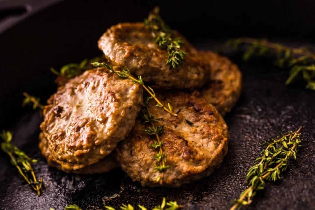 uicy turkey sausage patties cooked to perfection, garnished with fresh thyme on a black skillet.