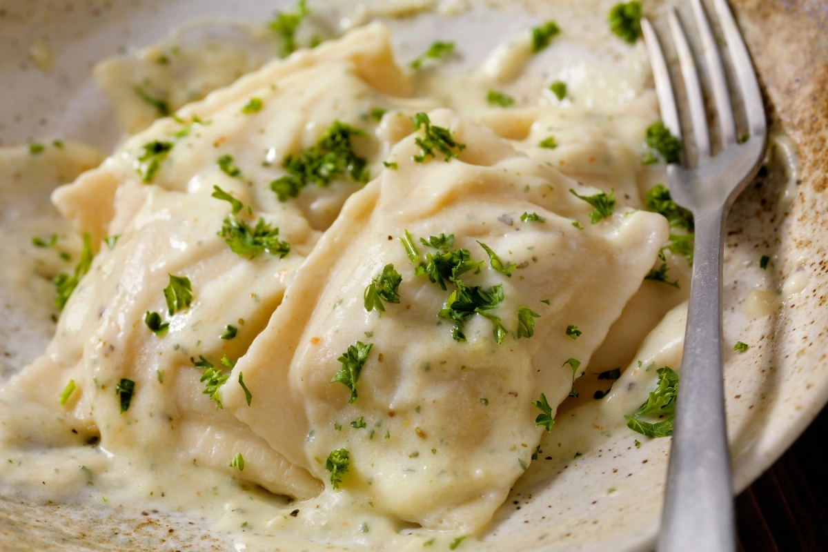 Lobster ravioli with Alfredo sauce and parsley garnish.