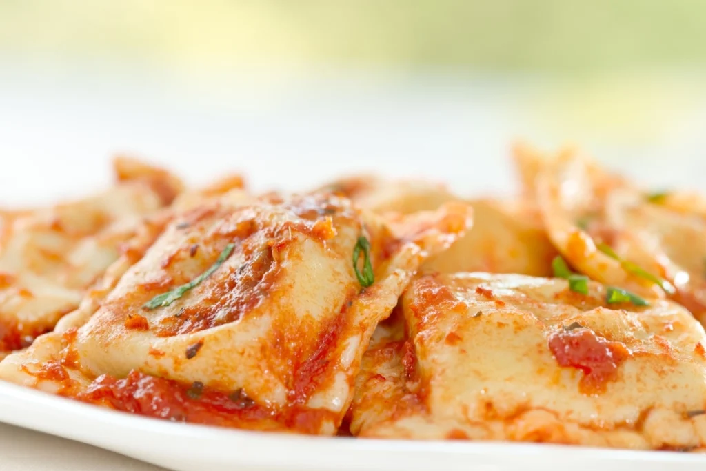 Lobster ravioli with marinara sauce and basil garnish.
