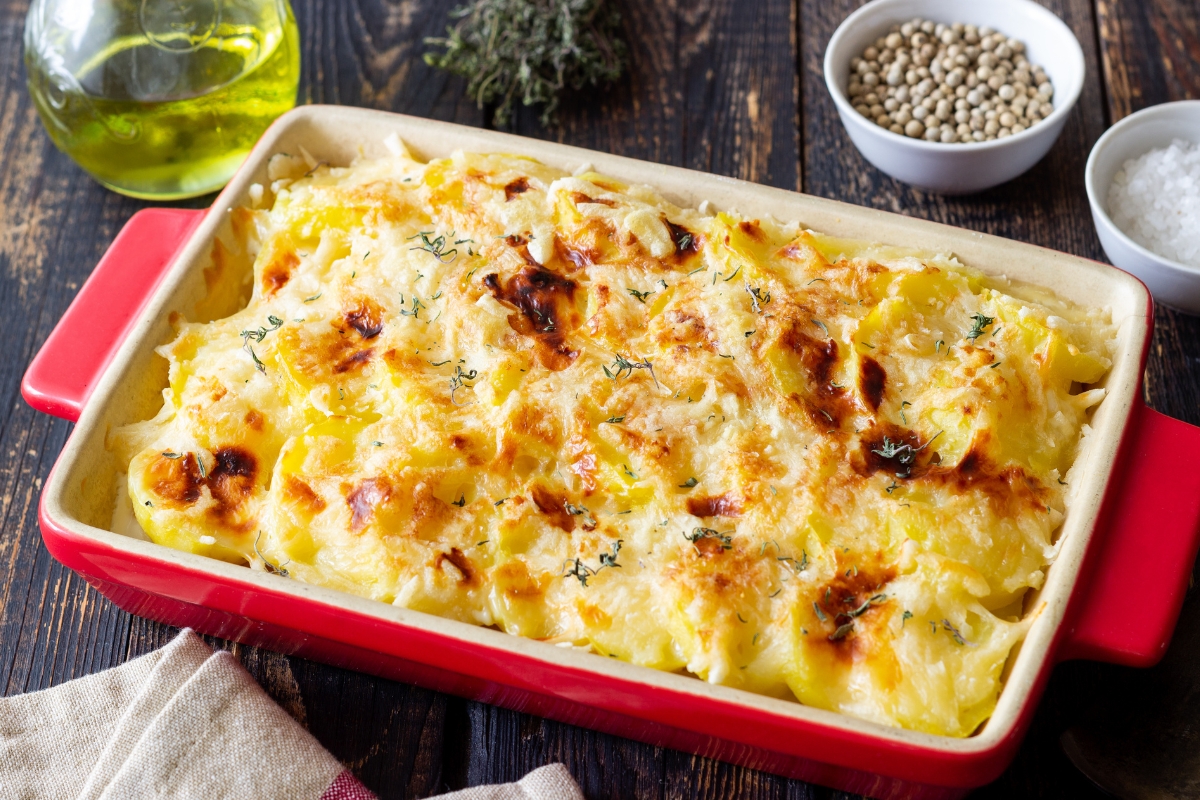 Creamy tuna noodle casserole topped with melted cheese in a red baking dish.