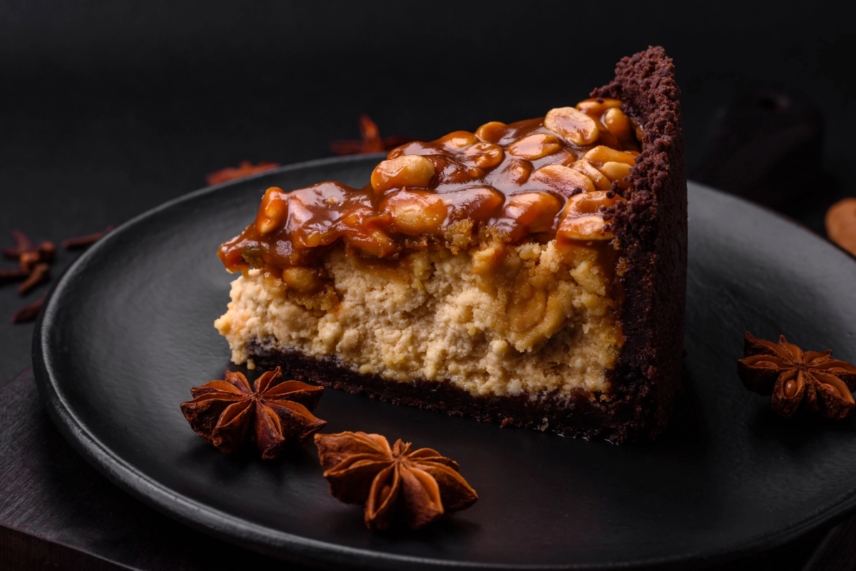 Slice of Snickers Cheesecake on a Black Plate