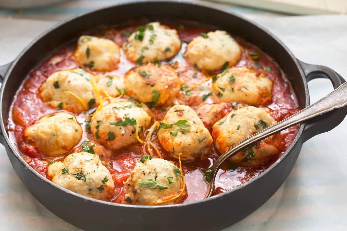 Chicken ricotta meatballs simmered in a rich tomato sauce, garnished with fresh herbs.