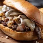 A Philly cheesesteak sandwich with melted cheese, sautéed onions, and tender beef on a toasted roll, served with waffle fries.