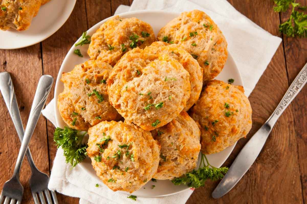 A plate of golden-brown crab-stuffed cheddar bay biscuits garnished with fresh parsley.