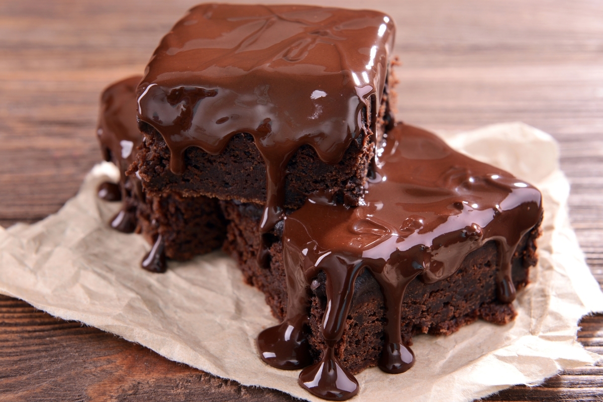 Decadent hot fudge brownies with a rich chocolate glaze dripping over the sides.